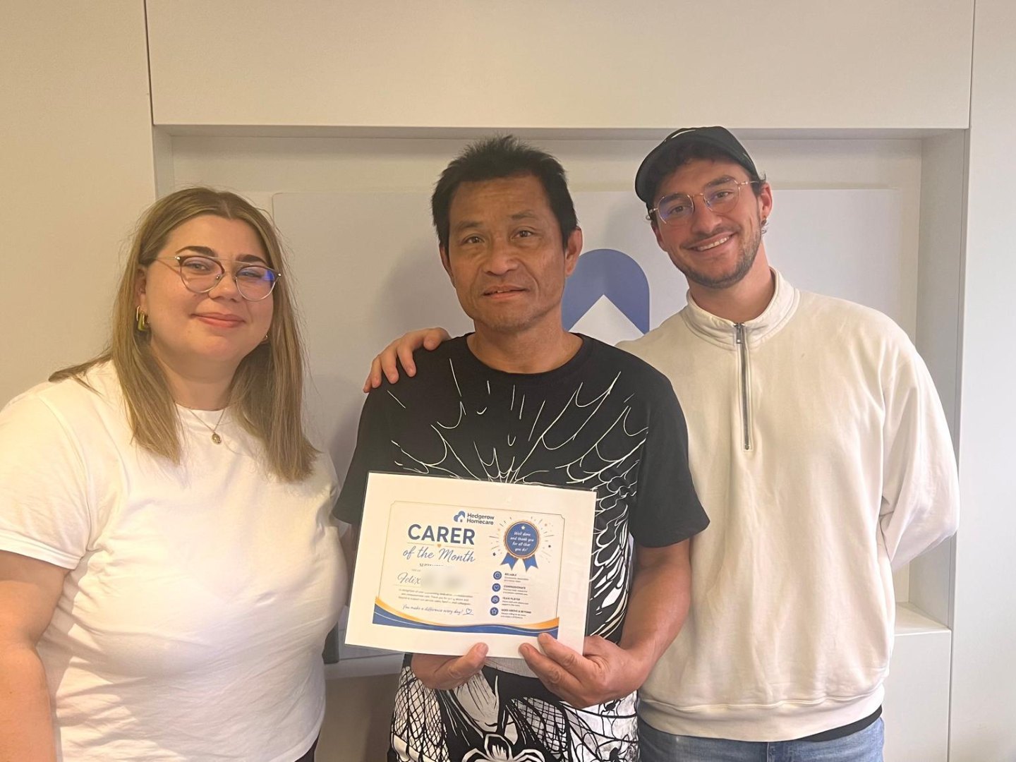 Felix P. holding his Carer of the Month certificate for September 2026, with two members of the Hedgerow office team