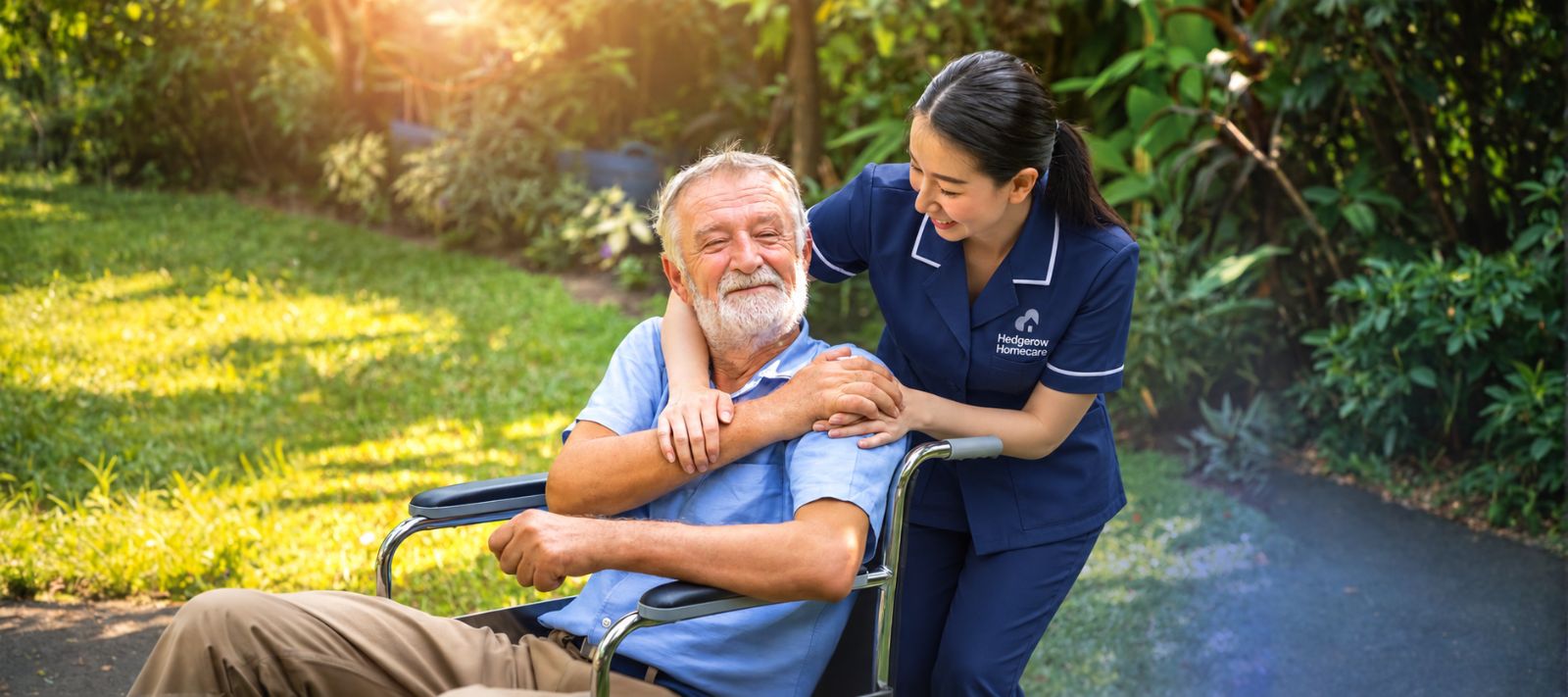 A carer with her arm around a smiling man in a wheelchair in a garden
