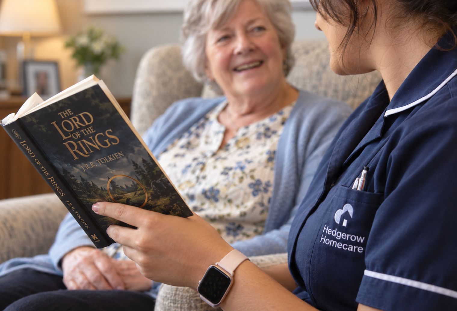 A carer reading aloud to an older woman in her armchair